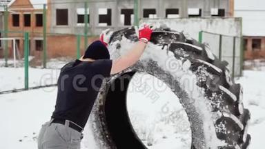 运动员在冬天举起一个大橡胶轮胎，做交叉健身运动